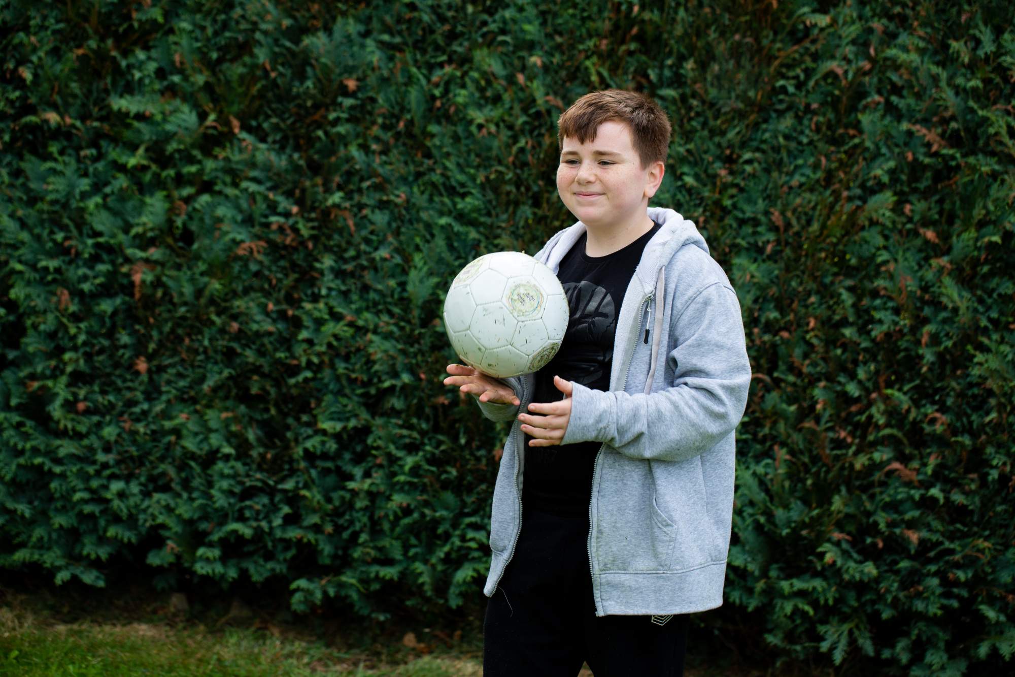 A young boy smiling and holding a football