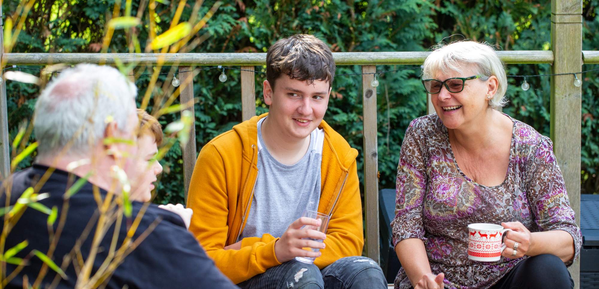A teenage boy sitting on the porch with his parents