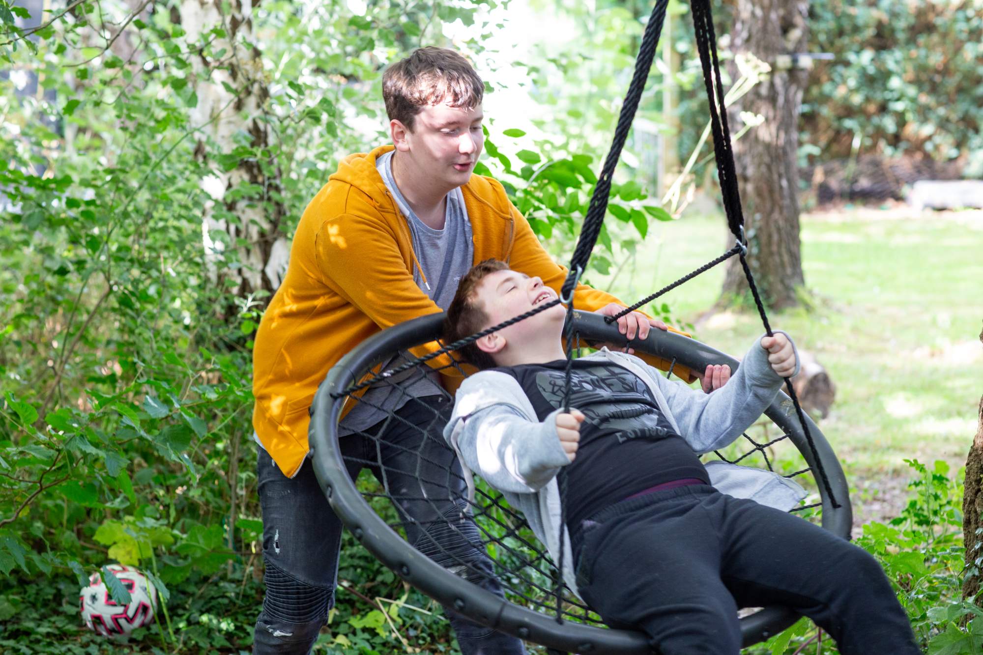 Two brothers playing on a swing