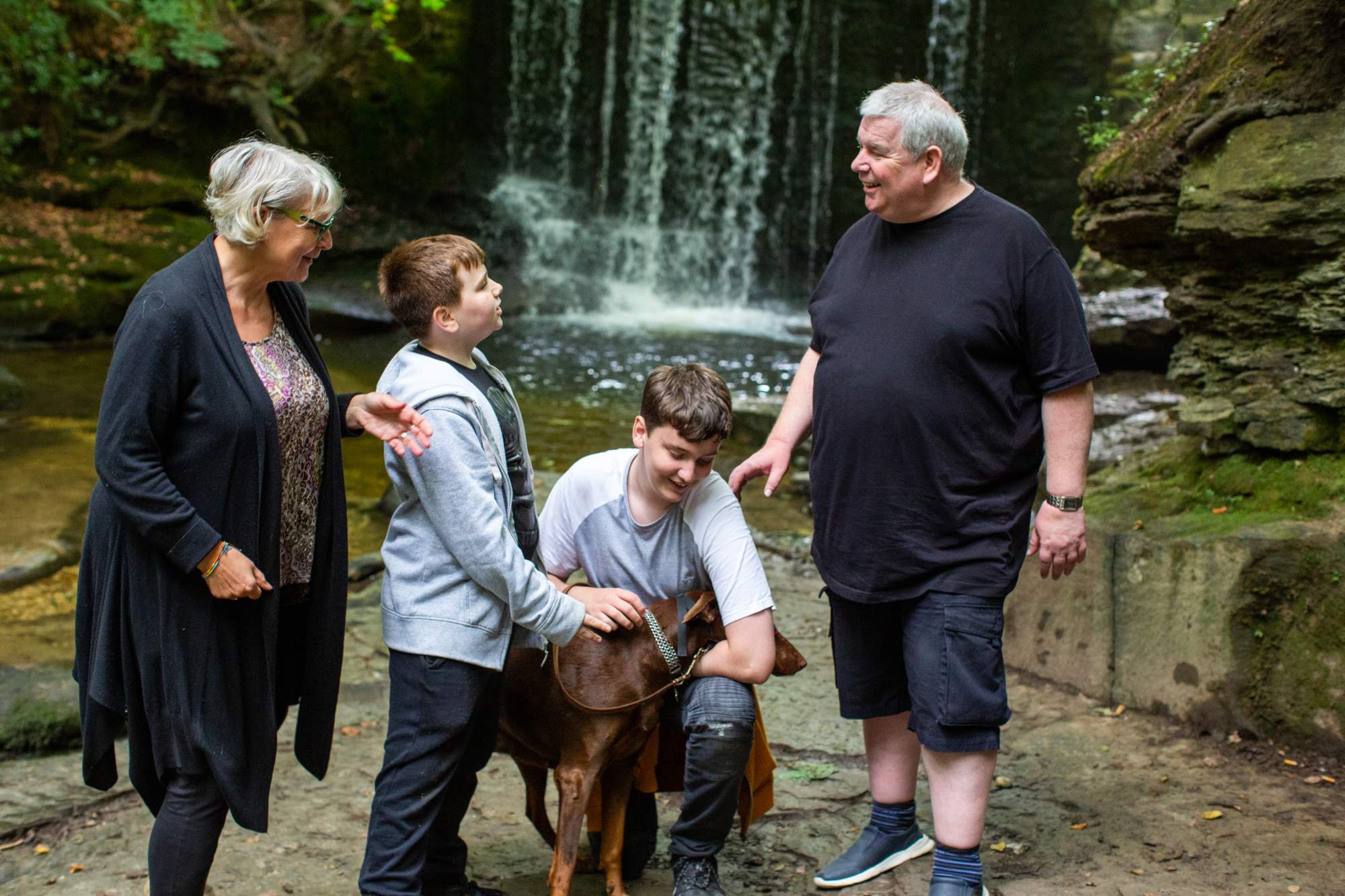 A family with their dog standing in front of a waterfall