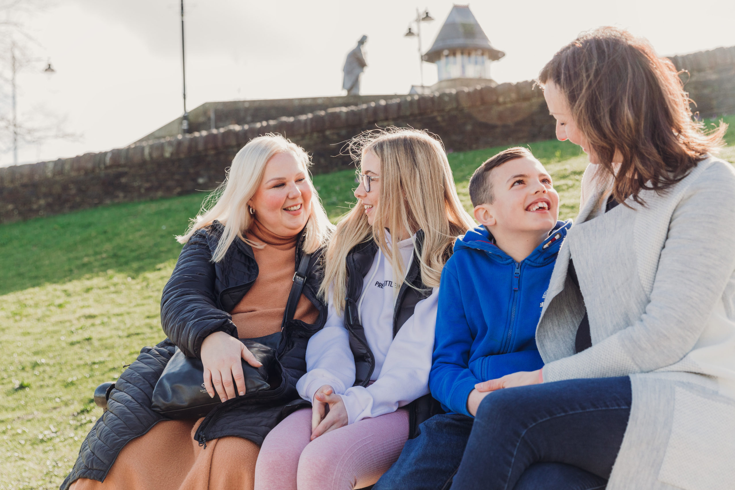 Two women, a boy and teenage girl sitting on a park bench