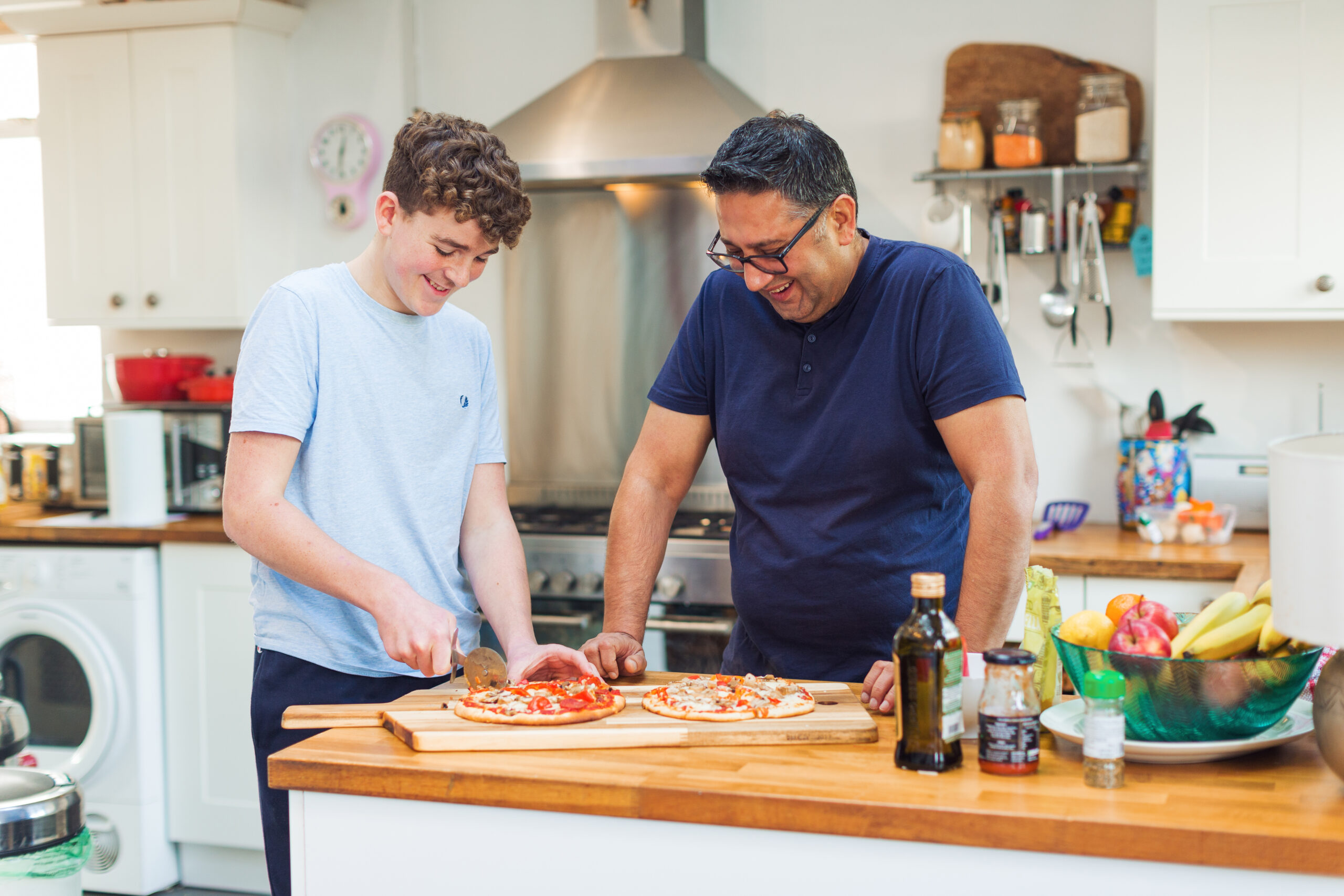 Man and boy in kitchen making pizza