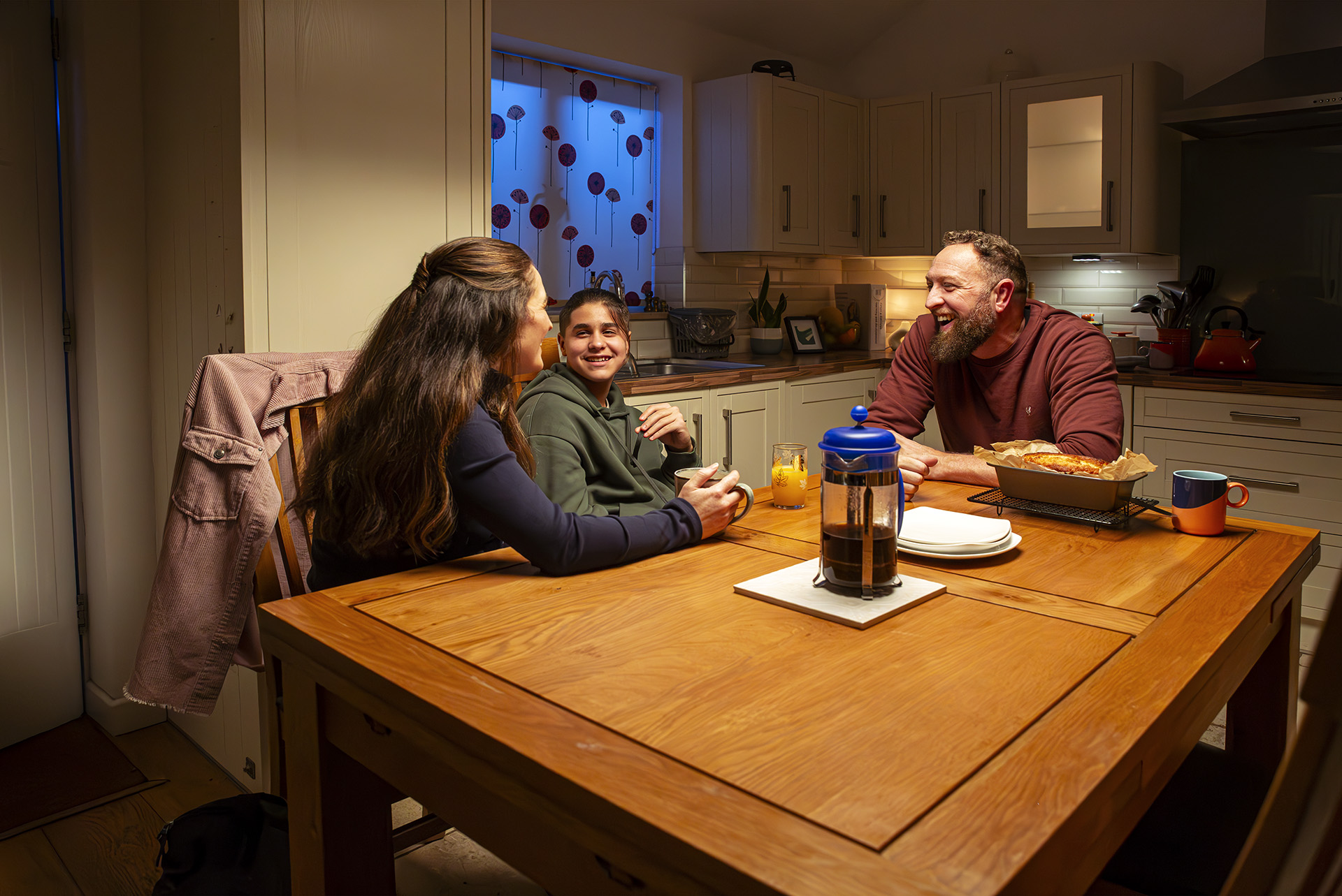 Social worker, teenage boy and male foster carer sat at kitchen table
